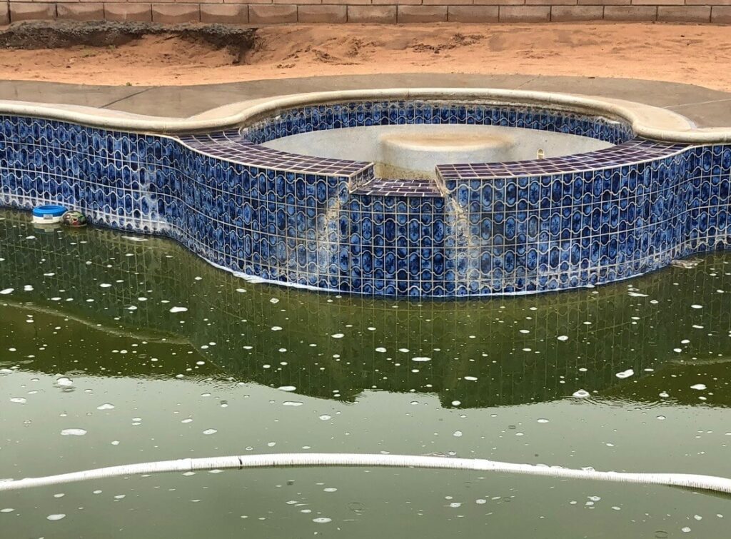 Pool waterline tile before professional calcium scale removal in the High Desert
